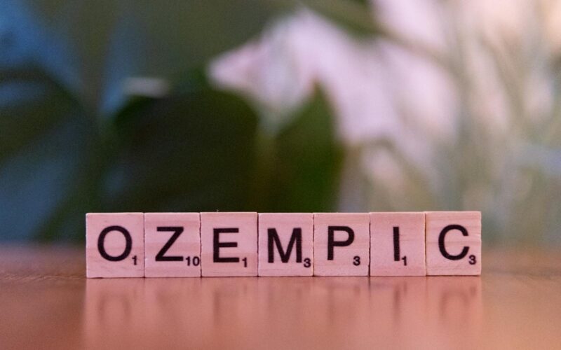Scrabble tiles spelling 'Ozempic' on a wooden surface, healthcare theme.