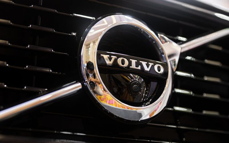 Detailed shot of Volvo emblem reflecting surroundings on a car grille, highlighting its classic design.